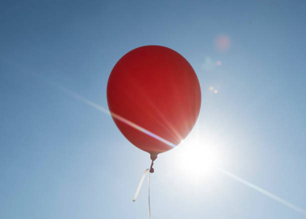 istock red balloon and blue sky background with sun 1316680575