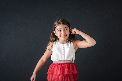 Cute little girl in orange dress posing over white background. Little princess girl portrait