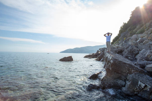 istock Man relaxes on rocky coastline at sunrise 1316681452