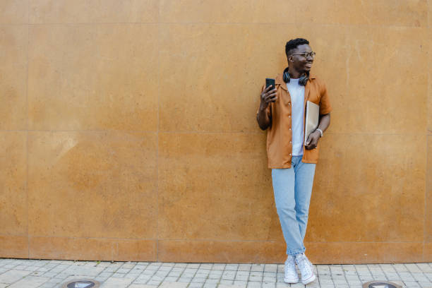 sorrindo jovem afro-americano usando telefone celular - men smiling headphones individuality - fotografias e filmes do acervo