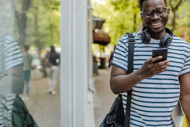 istock African-American confident young man is using mobile phone on the street 1316681863