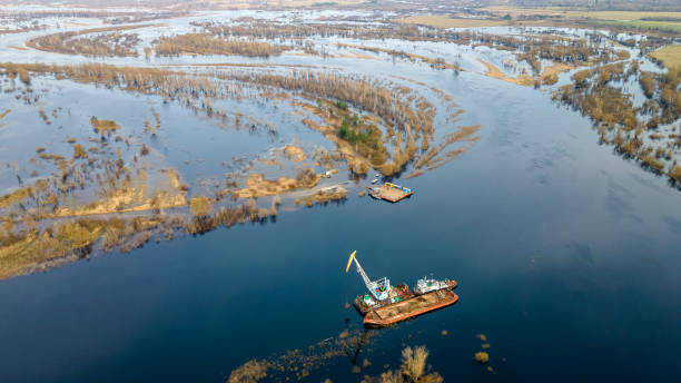 dredger está trabalhando para aprofundar a feira no rio. limpeza e aprofundamento por uma draga no rio. pôr do sol no rio. conceito industrial. - barge canal construction engineering - fotografias e filmes do acervo