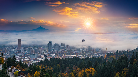 A photograph of Mt. Hood and Portland downtown with rolling fog and autumn foliage in shining sunrise and colorful clouds