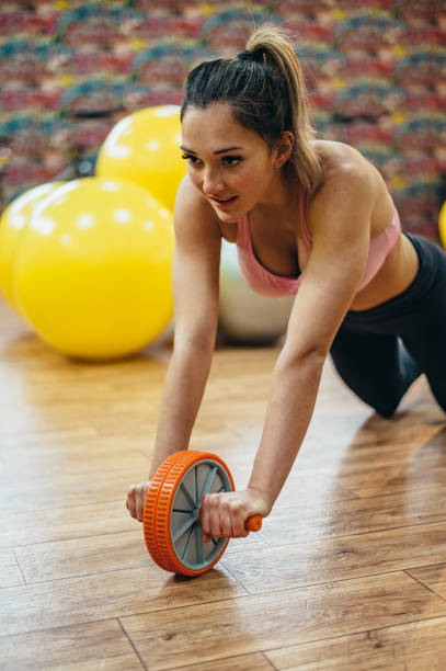 istock Woman training with ab wheel rollouts in the gym 1316685913