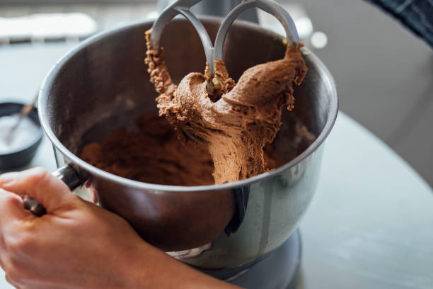 Baking at home: hand of an unrecognisable woman making chocolate chip cookie dough in her kitchen