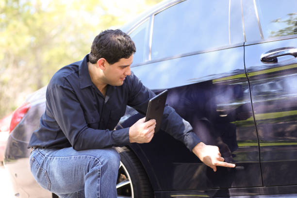 hombre de descenso latino inspecciona auto por daños. reclamaciones de seguro. - insurance car insurance agent auto accidents fotografías e imágenes de stock