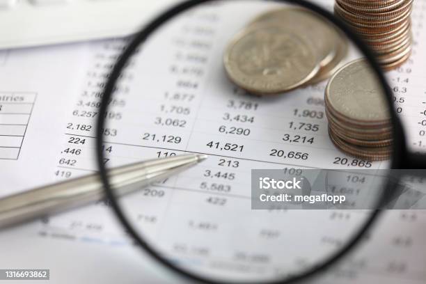 View At Financial Details In Table Thru Magnifying Glass Stock Photo - Download Image Now