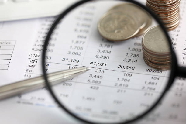 view at financial details in table thru magnifying glass - expense imagens e fotografias de stock