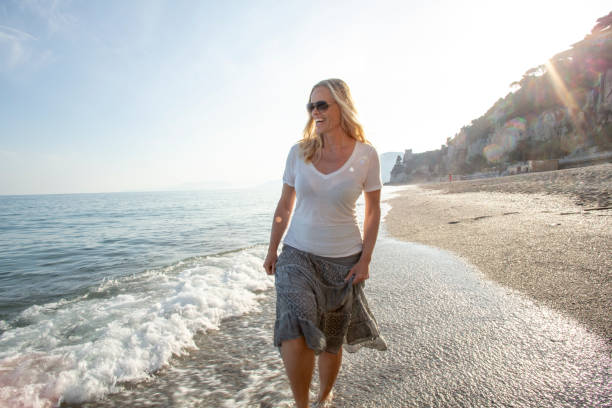 Woman walks along Mediterranean beach at sunrise