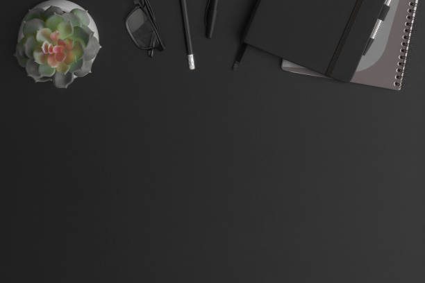 istock Black leather office table with notebook and green plant. Top view with copy space. Flat lay composition. 1316695655