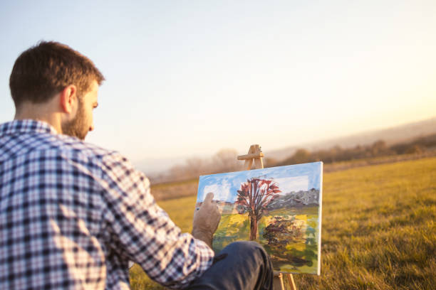 日没時にキャンバスに自然の中で絵を描く若者 - painting artist landscape painted image ストックフォトと画像