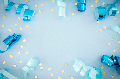 Gold ribbons and stars on a light blue background, with copy space.  
Party/ Celebration background.