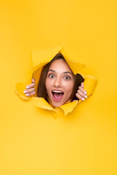 istock Excited woman peeking out torn paper 1316709662