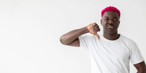 Refusing man. Dislike gesture. Bad choice. Looser blaming. Skeptic emotion. Stylish disgusted african guy with bright pink hair showing disapproval sign isolated white copy space.