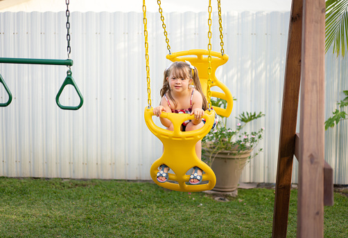 Little blond girl playing on a yellow swing