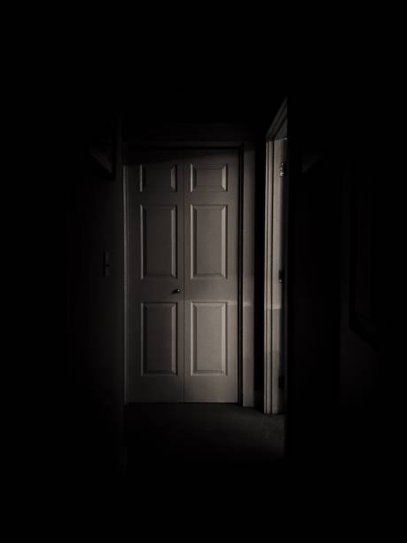 Dark Hallway Light emitting from a room in a dark hallway. haunted house stock pictures, royalty-free photos & images