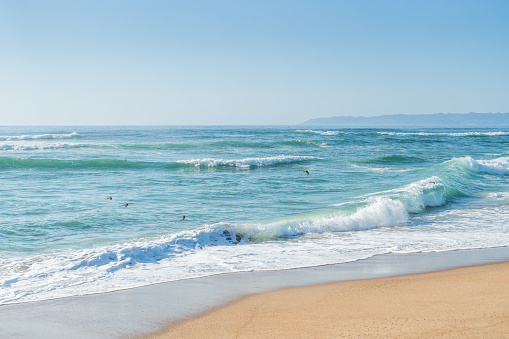 Seascape background. Turquoise colored sea, sandy beach, and clear blue sky. Summer concept, copy space for text