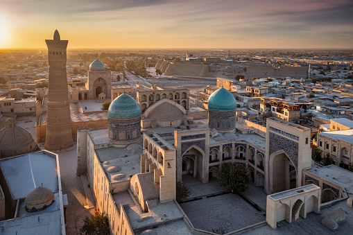 Bukhara Uzbekistan. Sunset over the famous Kalyan Poi Kalon, Poi Kalan or Po-i-Kalyan and Kalon Mosque with courtyard in the old town of Bukhara - Buxoro - Бухорo. Aerial Drone Point View at Sunset. Itchan Kala, Bukhara, Khorezm Region, Uzbekistan, Central Asia.