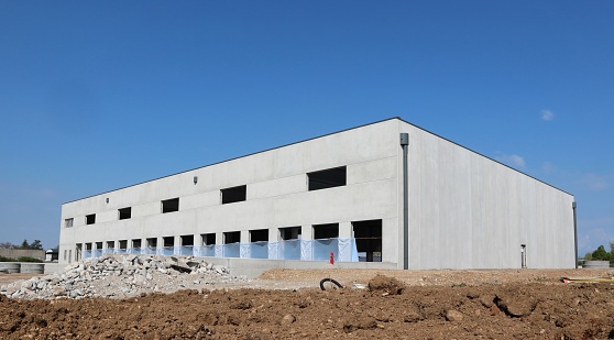 Large industrial warehouse made of prefab concrete blocks, under construction. The external walls are already finished