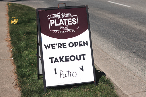 Courtenay, Canada - April 22,2021: View of sign We are open, Take Out, Patio  at the entrance of local restaurant in Courtenay due to COVID-19(Coronavirus)