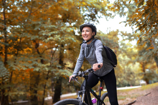 młoda i szczęśliwa kobieta w dresie na rowerze górskim cieszy się w ciągu dnia jazdy po parku - park and ride zdjęcia i obrazy z banku zdjęć