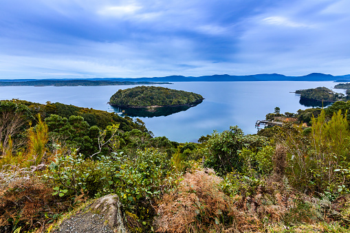 This July 2020 long-exposure image shows Whaka a Te Wera Paterson Inlet on Rakiura Stewart Island, Aotearoa New Zealand on a cloudy day. Rakiura National Park is on the opposite side of the inlet.
