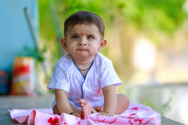 Baby boy is lying on tummy. The baby boy poses and plays with a pacifier.