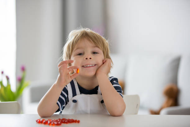 симпатичный маленький ребенок, малыш мальчик, есть альфа омега-3 ребенка дополнение витаминные таблетки в домашних условиях - vitamin a стоковые фото и изображения