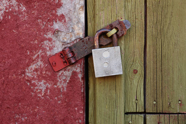 a barn lock on an old barn with rusty hinges, a green plank door and a peeling wall stock photo