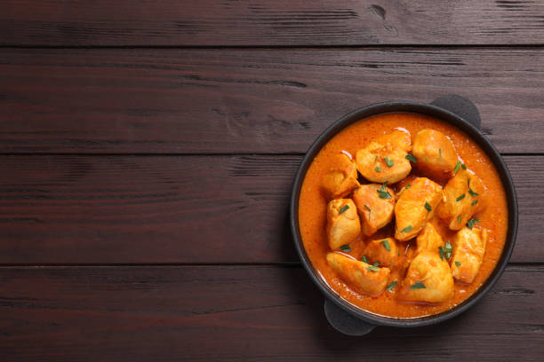 istock Delicious chicken curry in pan on wooden table, top view. Space for text 1316759948