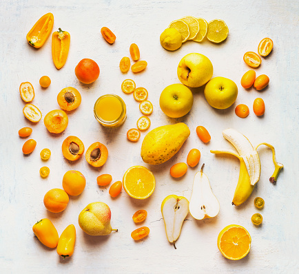Various yellow and orange color fruits and vegetables on white table background. Flat lay. Food layout. Color diet. Benefits of yellow and orange color food. Healthy eating