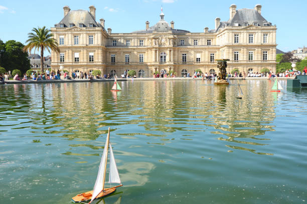 The Palais du Luxembourg at the Jardin du Luxembourg in Paris A view of the Palais du Luxembourg and Senate at the Jardin du Luxembourg in Paris with a toy sailboat in the foreground on a sunny summer day. luxembourg paris stock pictures, royalty-free photos & images