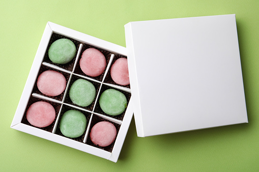 Many different delicious mochi in box on green background, top view. Traditional Japanese dessert
