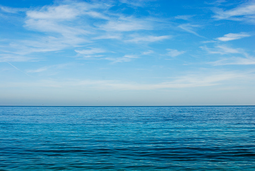 turquoise blue sea horizon with two thirds of blue sky with white clouds, background with copy space