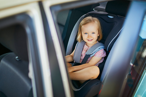 Adorable toddler girl in modern car seat. Little kid traveling by car. Child safety on the road. Trip with an infant.