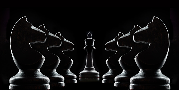 Silhouettes of chess on a black background. Chess queen and chess horse pieces.