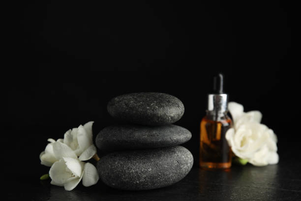istock Stack of grey spa stones, flowers and oil on black table 1316768912