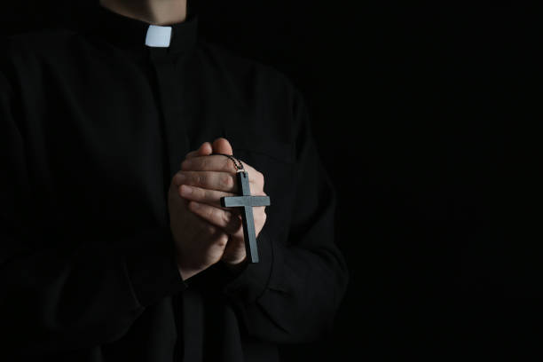 priester mit kreuz auf dunklem hintergrund, nahaufnahme. platz für text - priester stock-fotos und bilder
