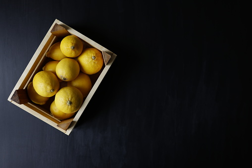Istanbul, Turkey-May 4, 2021: A case of lemons on a black wooden background. Full Frame, Still life, Flat lay. Shot with Canon EOS R5.