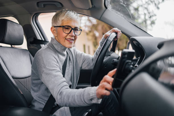 Senior female driver setting navigation on smart phone before a drive.