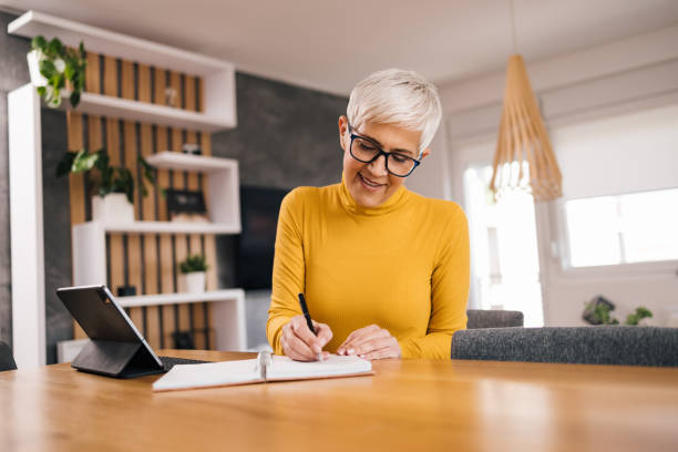 istock Beautiful senior woman taking notes at home office. 1316770265