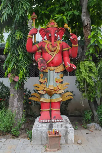 Four-armed red elephant statue in the middle of the Thai jungle.