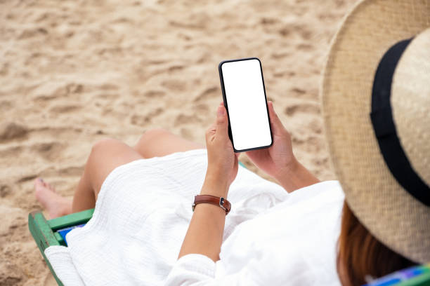 istock a woman holding black mobile phone with blank desktop screen while lying down on a beach chair 1316772631