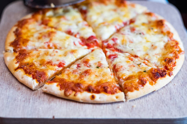 istock Cheese pizza sliced up on a wooden cutting board 1316772752