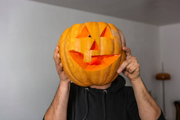 istock Man holding big pumpkin in front of his face 1316772869