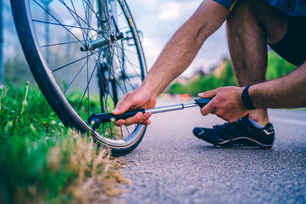 Man pumping bicycle wheel Young man cyclist pumping bicycle wheel outdoor air pump stock pictures, royalty-free photos & images