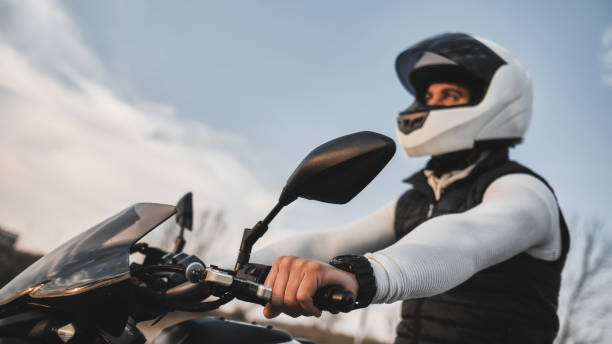 verticale d’un jeune homme conduisant une moto et utilisant un casque. - motorcycle mirror biker glove photos et images de collection