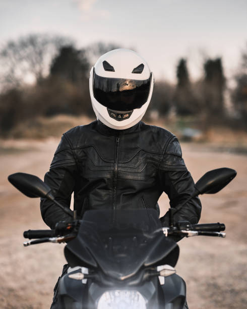 verticale d’un jeune homme s’asseyant sur la moto et utilisant une veste et un casque en cuir. - motorcycle mirror biker glove photos et images de collection