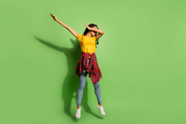 foto completa de uma linda e escura senhora pele vestida camiseta amarela saltando dab fundo de cor verde isolada - dab dança - fotografias e filmes do acervo