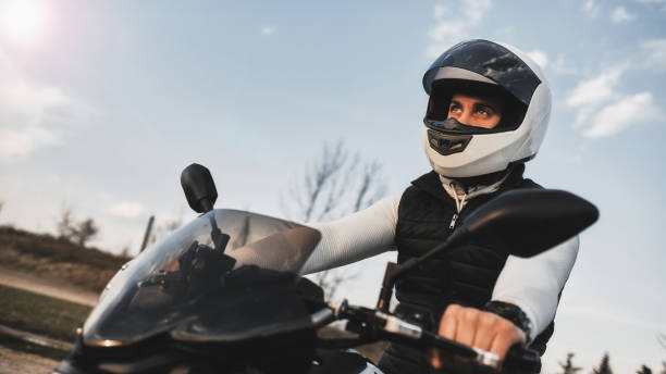 verticale d’un jeune homme conduisant une moto et utilisant un casque. - motorcycle mirror biker glove photos et images de collection